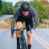 Cyclist riding a country road wearing black Finvizo UPF arm sleeves in summer heat