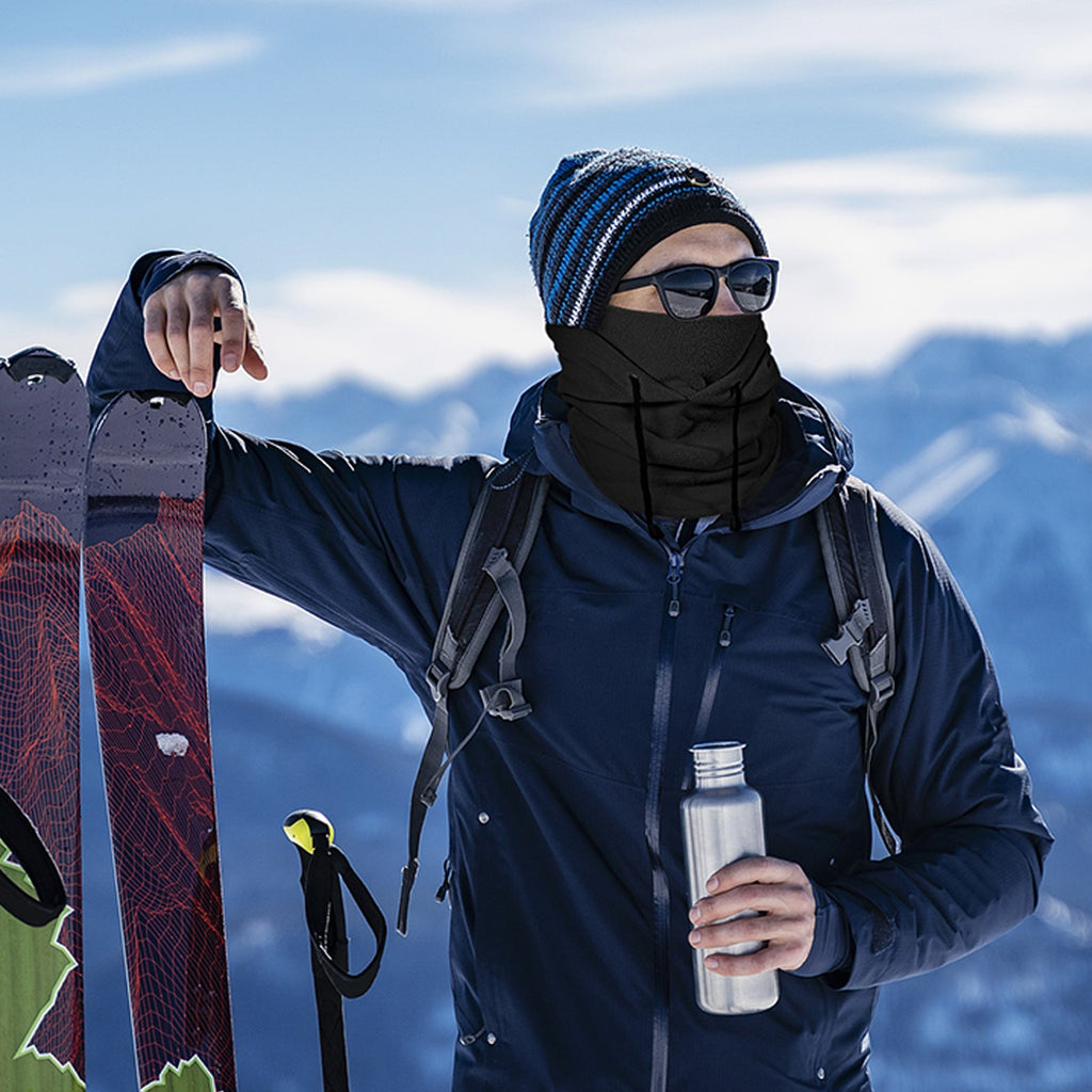 Skier wearing a fleece balaclava on a snowy mountain ridge