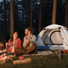 Couple relaxing by their tent at an evening campsite - campsite gear usage guide