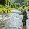 A fly fisher wading in a sunlit river wearing a sun hoodie and neck gaiter