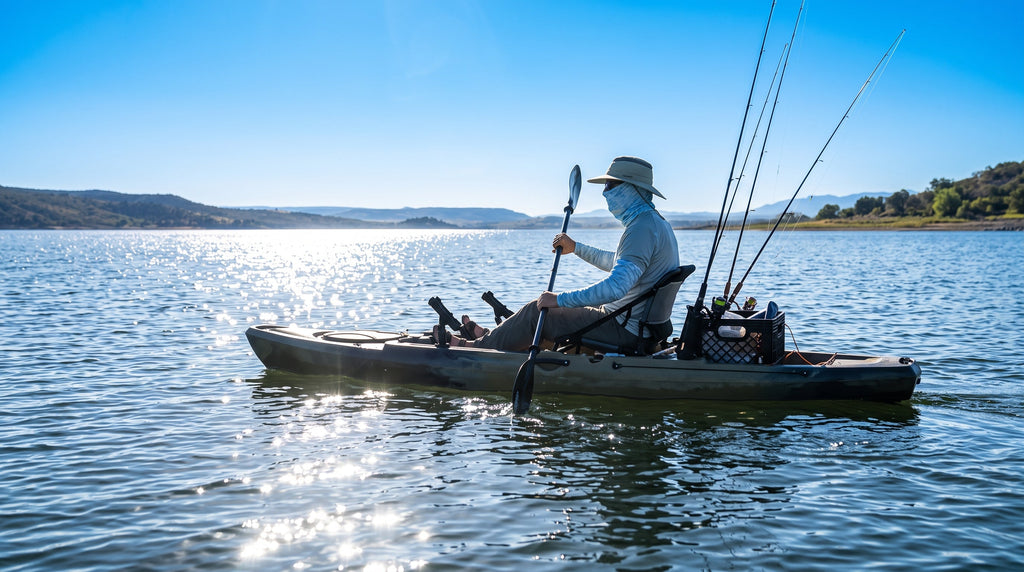 A kayak angler on bright open water wearing a neck gaiter, sun sleeves and wide-brim hat