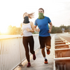 Two runners wearing Finvizo cooling neck gaiters on bridge at sunrise