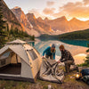 couple setting up 2 person tent at lakeside campsite during golden hour