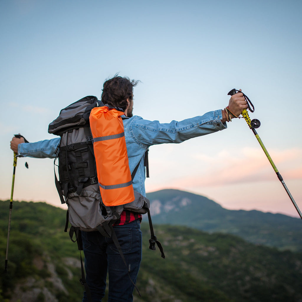 Solo backpacker with a backpack watching sunset on a mountain ridge near a 1 person tent campsite