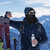 Skier wearing a fleece balaclava on a snowy mountain ridge