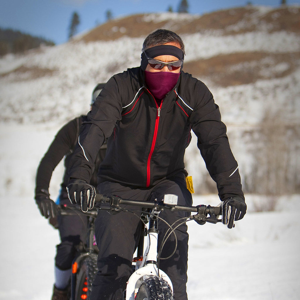Man riding a bike through snow wearing a fleece neck warmer over his face