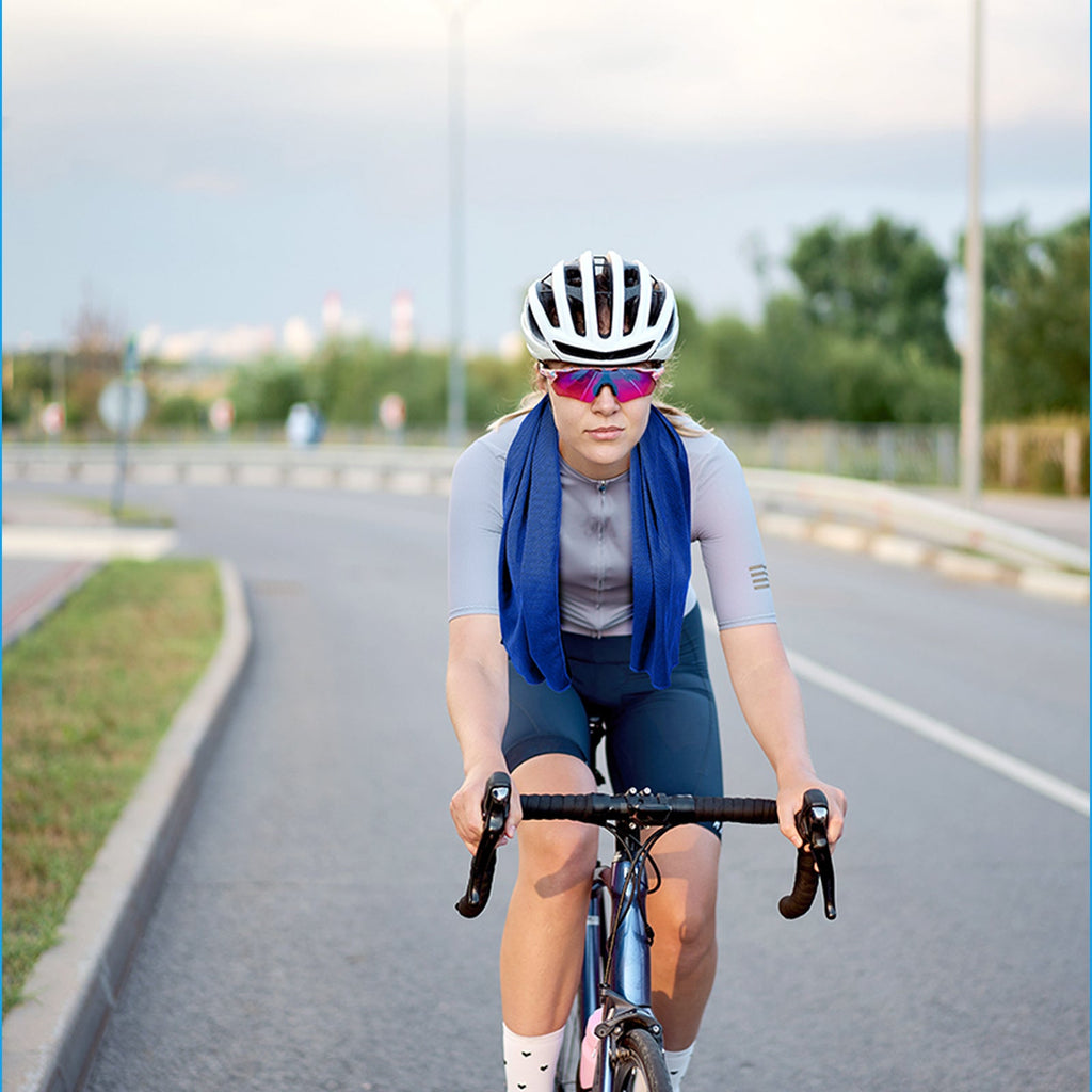 Finvizo cooling towel in blue worn by a cyclist riding on a hot road