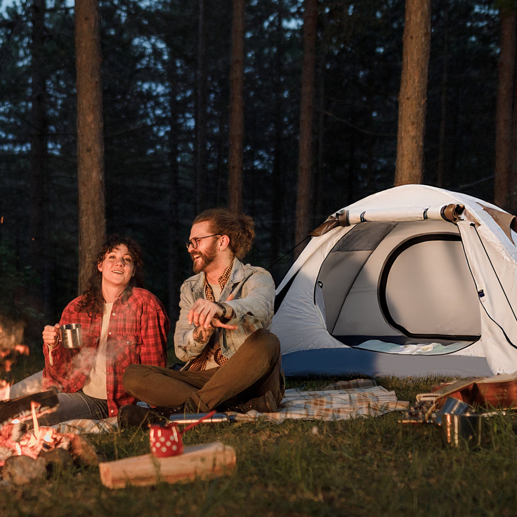 Couple relaxing by a campfire in front of their Finvizo backpacking tent at dusk