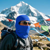 Man wearing a blue balaclava and sunglasses in a snowy mountain base camp