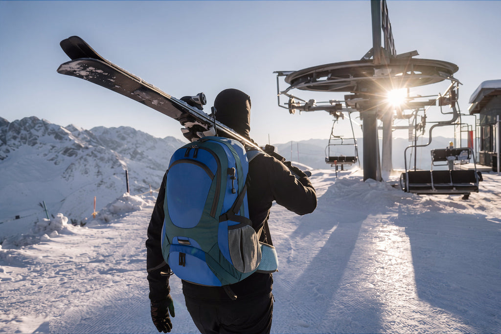 Finvizo 50L backpack opened by a skier organizing gear on a snowy mountain summit - ski trip packing beyond slopes