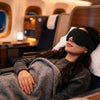 Woman sleeping peacefully on airplane wearing Finvizo 3D contoured blackout sleep mask for travel comfort