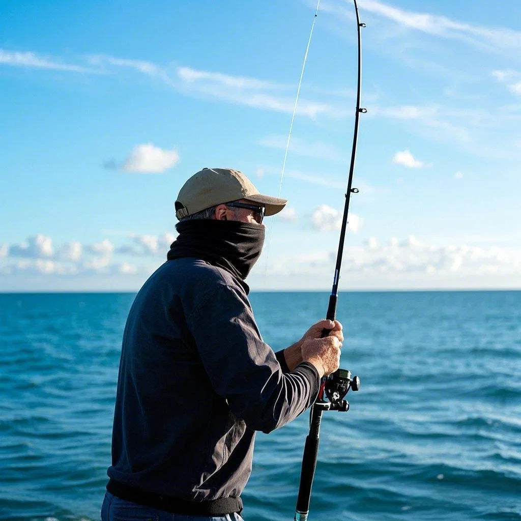 Angler wearing Finvizo neck gaiter and hat fishing from a boat on blue saltwater