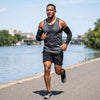 A man jogging on a sunny riverside path wearing fitted compression arm sleeves