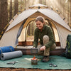 A complete basic camping kit laid out on a tarp at a forest campsite for a beginner camper