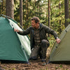 A camper comparing two camping tents side by side in a forest clearing