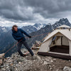 A camping tent with taut guy lines holding against strong wind on a mountain ridge