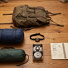 Camping gear spread on a wooden floor with a notebook for pre-purchase planning