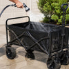 Rinsing sand off a Finvizo folding wagon in a driveway after a beach trip