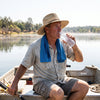 An angler on a boat in harsh summer sun with a damp cooling towel around the neck