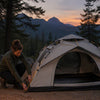 Woman solo camper securing her Finvizo tent at dusk with warm lantern light